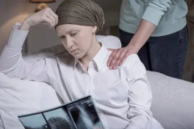 Person in headscarf reviewing chest X-ray with support, symbolizing cancer diagnosis and emotional care.