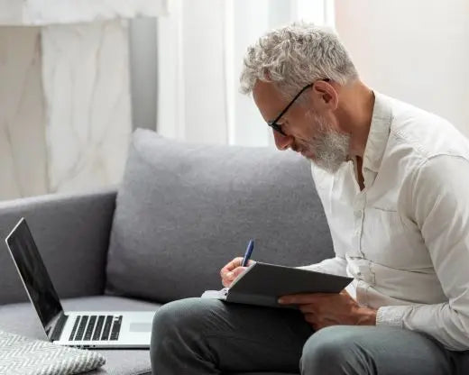 senior-man-home-studying-laptop-taking-notes