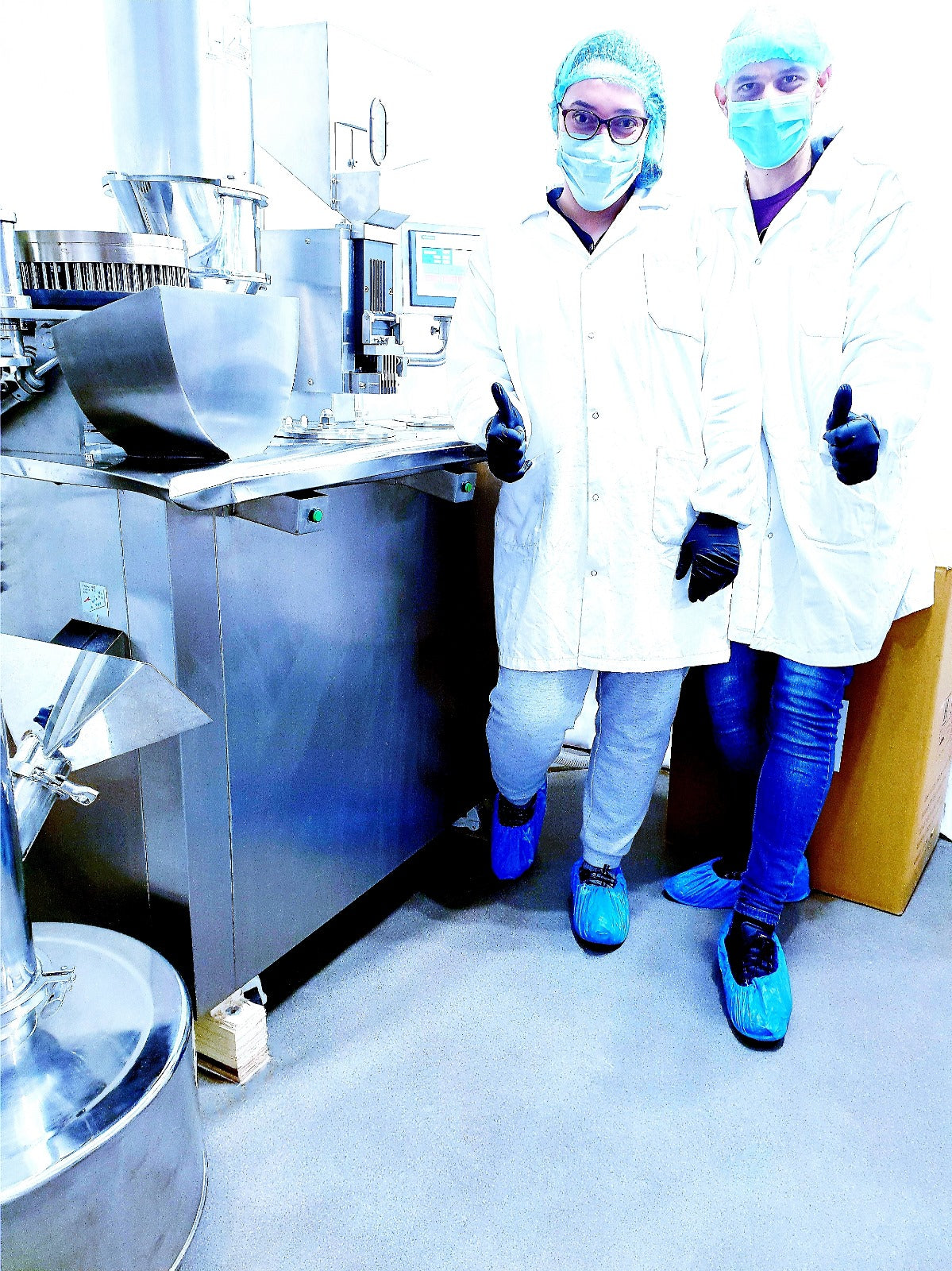 Two people in a laboratory setting wearing protective gear.